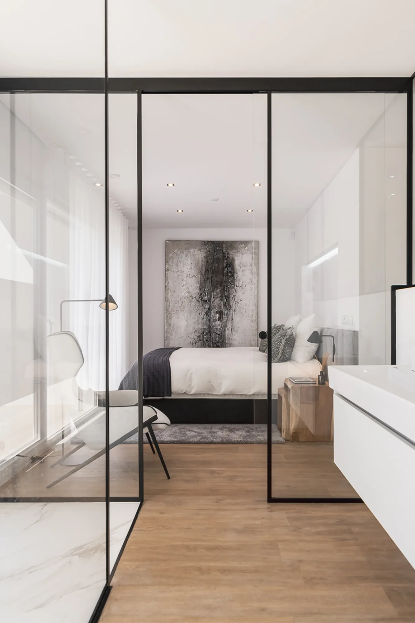 Suite com divisória envidraçada de perfil metálico negro a separar a casa de banho.